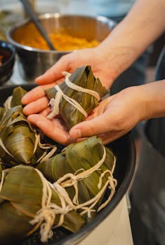 Close-up of hands crafting rice dumplings wrapped in bamboo leaves in Tokyo, Japan.