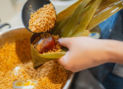 A close-up view of a person preparing Japanese rice dumpling in Tokyo using bamboo leaves.