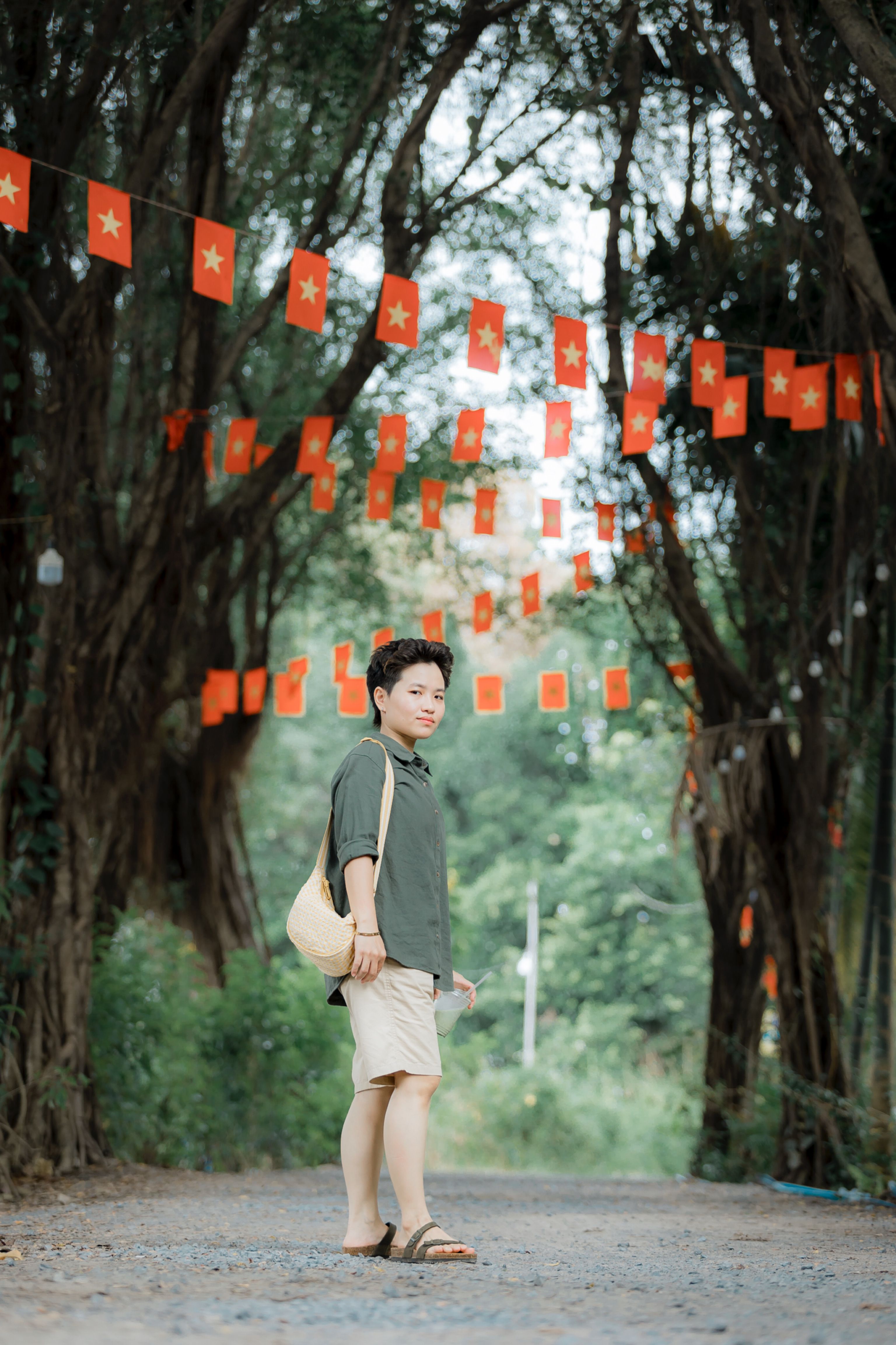 Man Walking Under Red Flags in Tree-Lined Pathway · Free Stock Photo