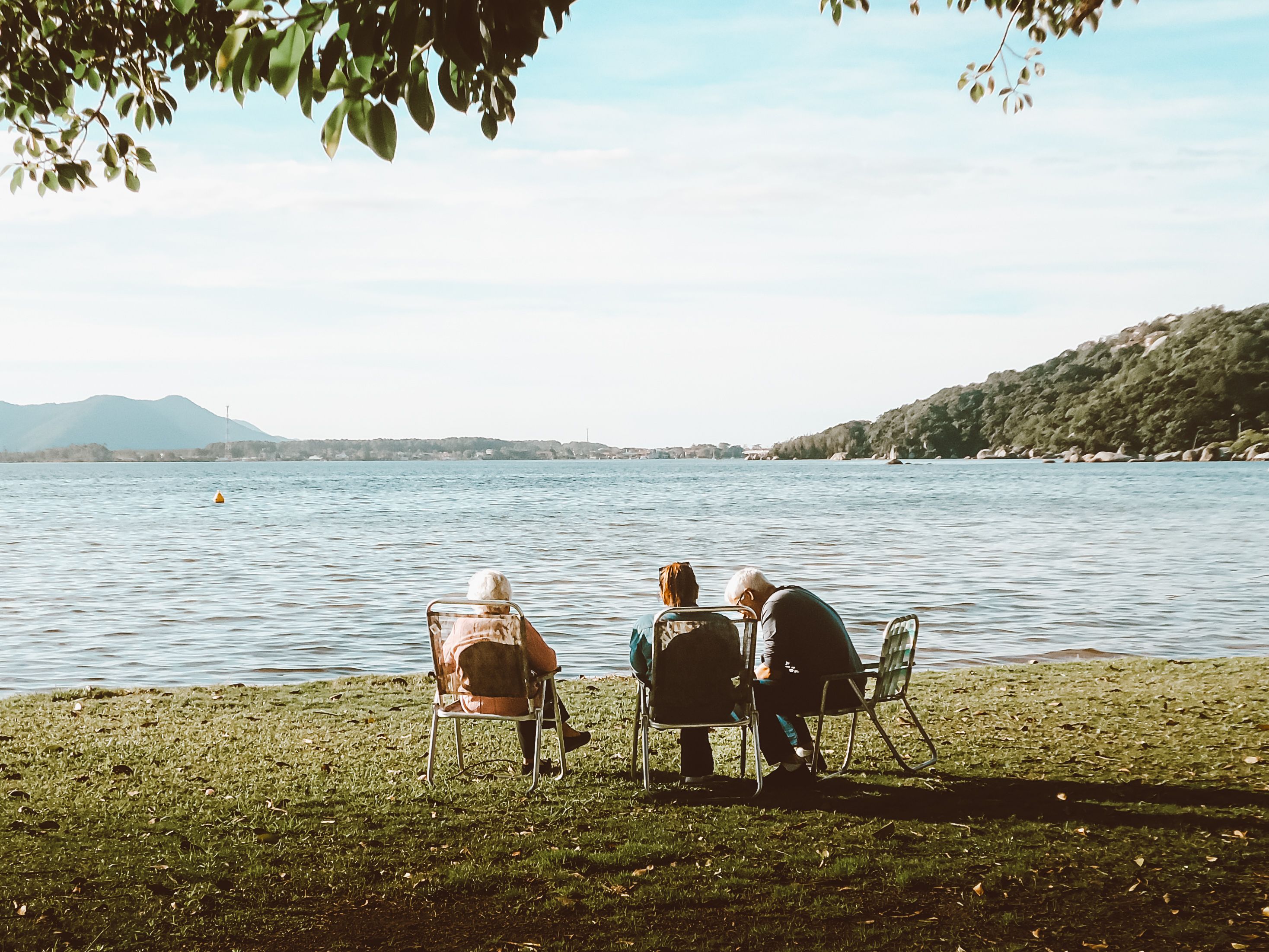 Three people enjoying a peaceful afternoon by the lake with scenic views.