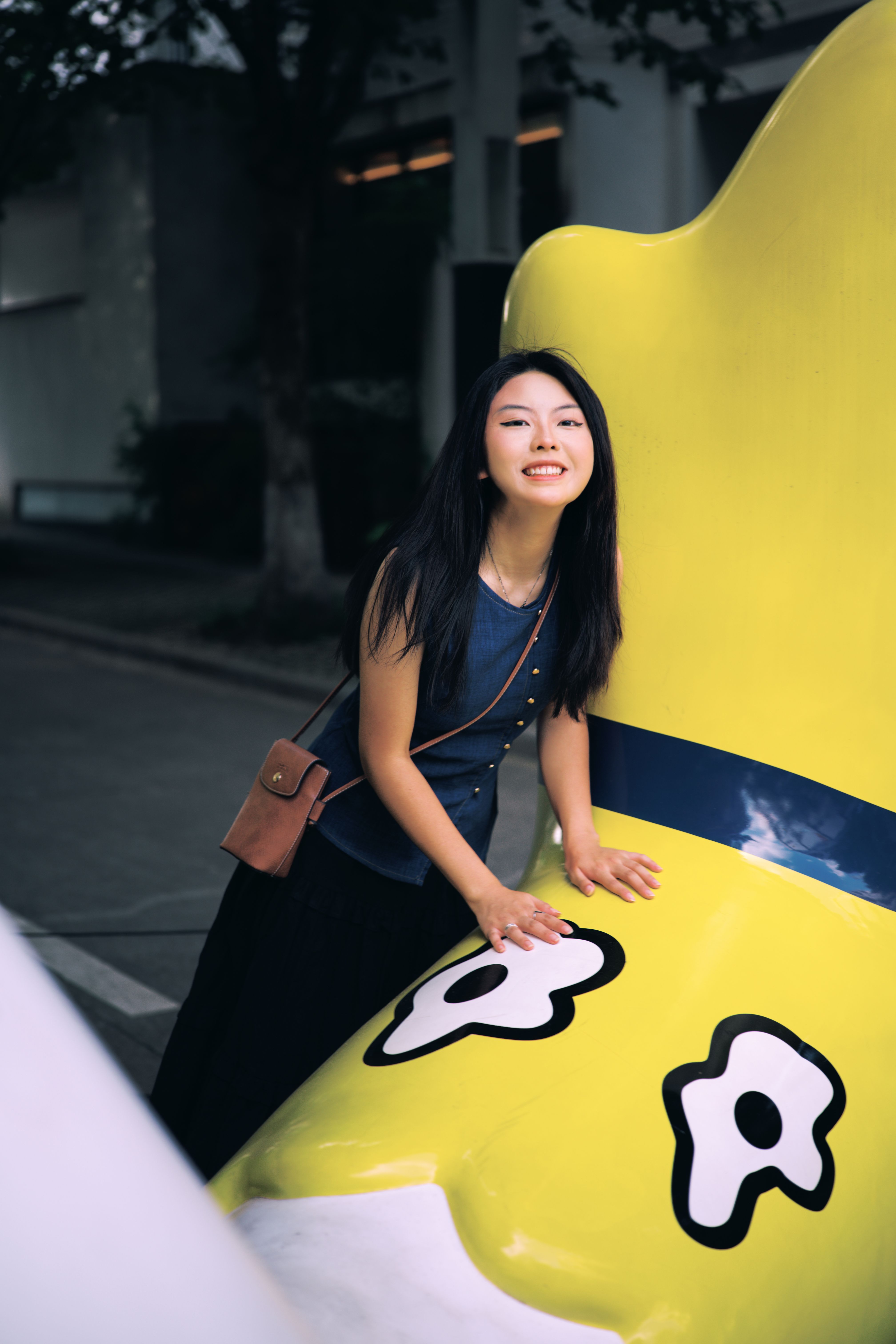 Young Woman Posing with Yellow Sculpture Outdoors · Free Stock Photo
