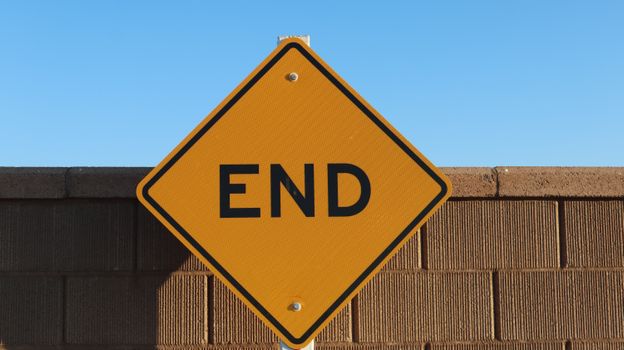 Yellow 'END' sign in Elk Grove, California, with a bright blue sky and brick wall backdrop.