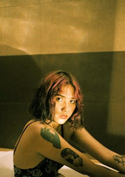 这幅描绘室内纹身女子的肖像喜怒无常，突出了艺术表达力和内省情绪