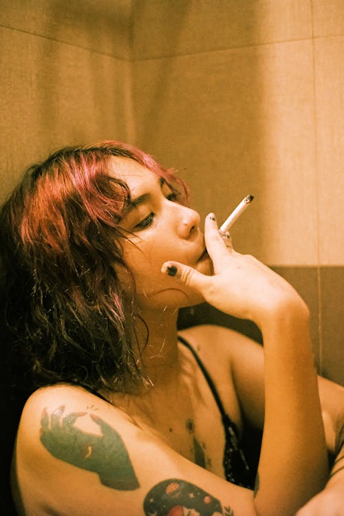 бесплатная Женщина курит, опираясь на стену Стоковое фото