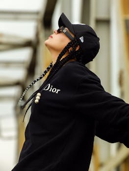 Portrait of a fashionable woman with braided hair and cap enjoying the outdoors in a relaxed pose.
