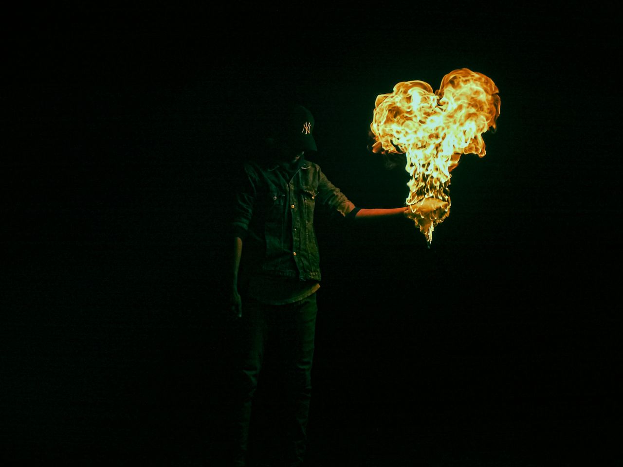 a person in a dark setting holding a flame shaped like a heart creatin