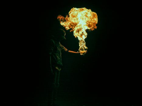 A captivating image of a fire performer creating dramatic flames in a dark setting.