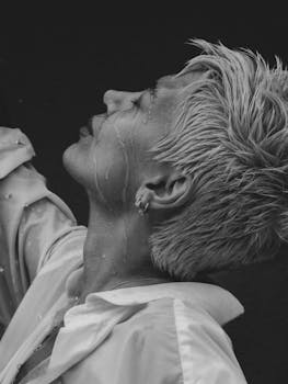 Evocative black and white portrait of a woman feeling the rain, capturing emotion and grace.