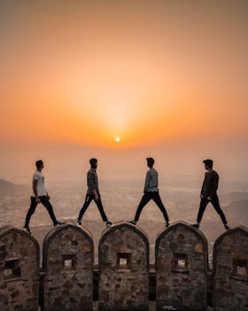 A group of men walking atop ancient walls in Jaipur, India, at sunset.