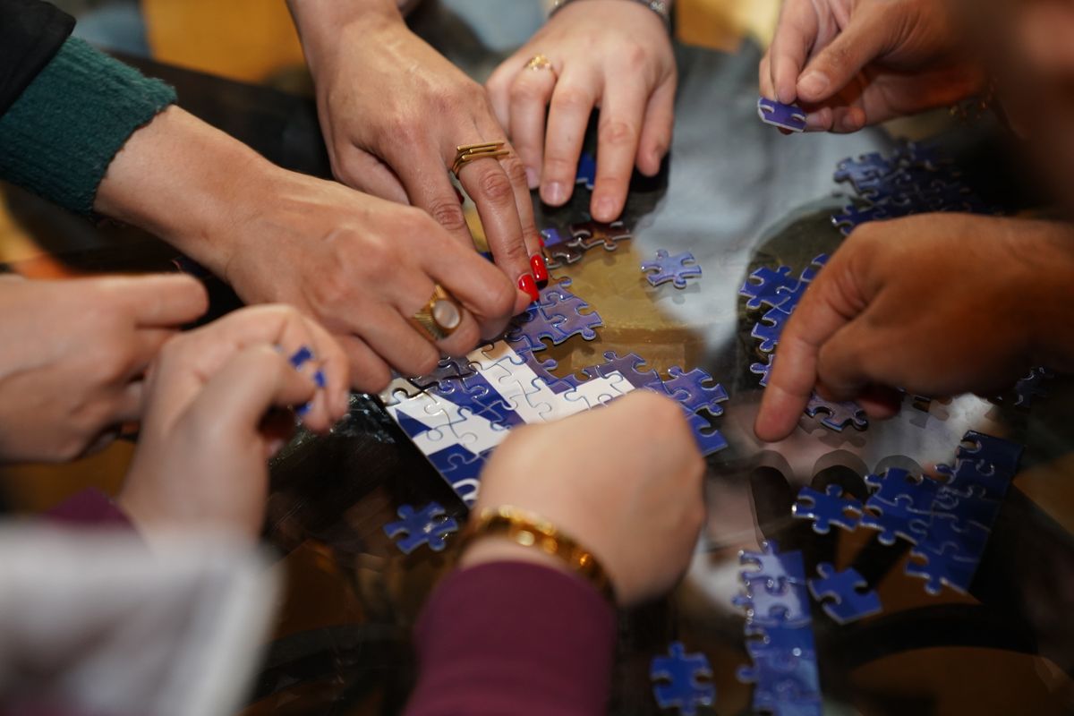 A group of colleagues working together to assemble a puzzle around a table