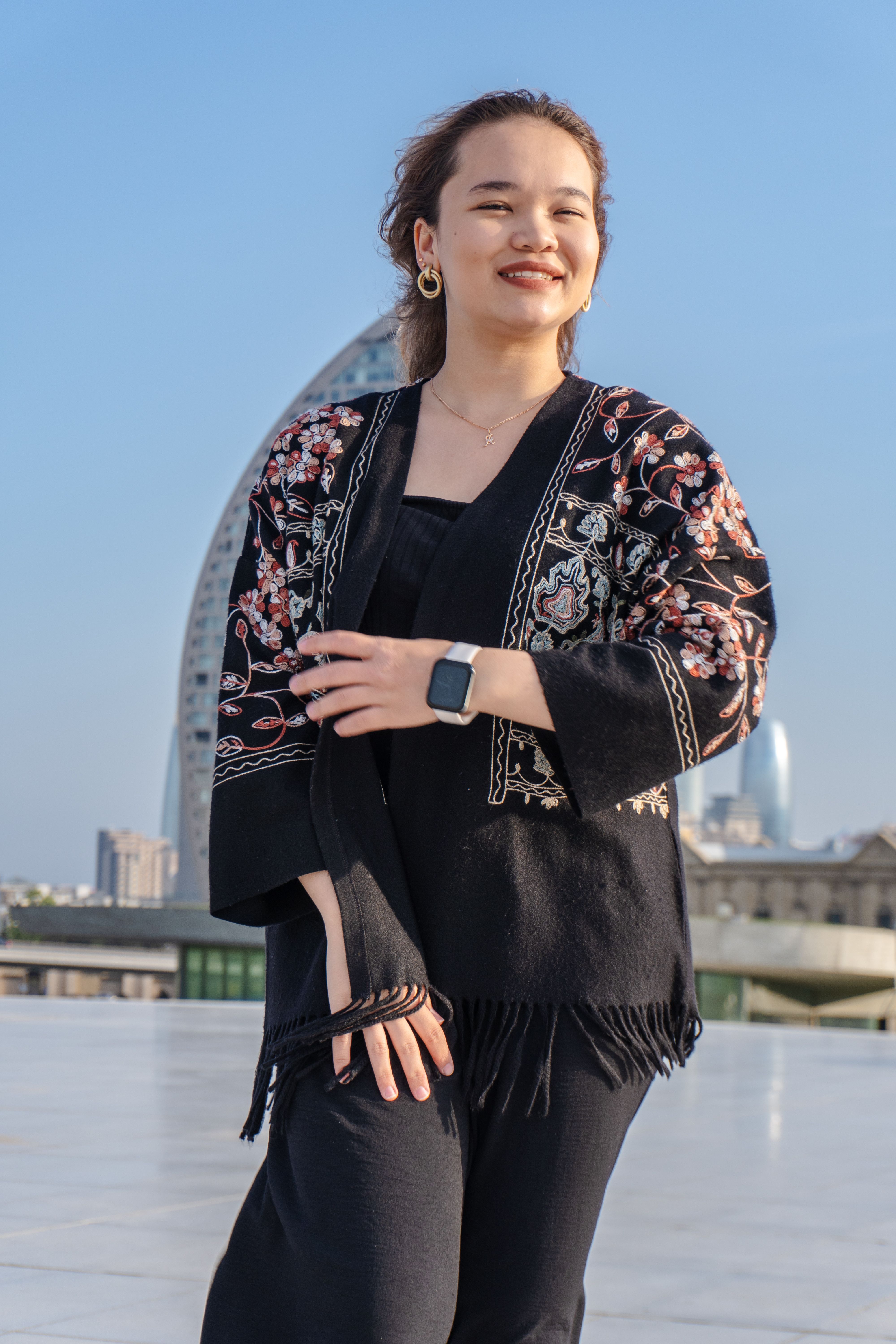 Smiling woman in traditional embroidered attire enjoys a sunny day outside