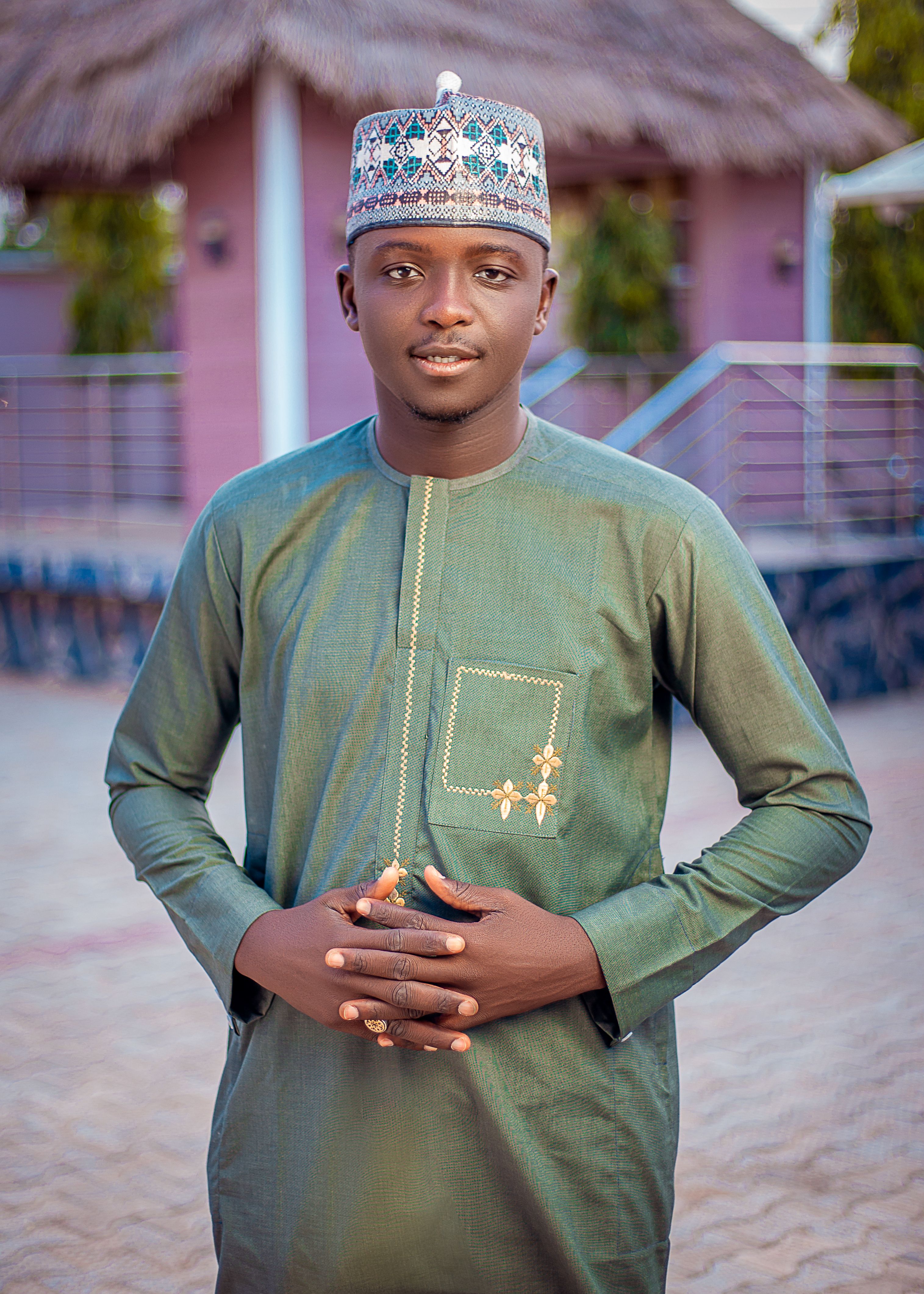 Confident young man in traditional attire posing outdoors, showcasing cultural apparel.