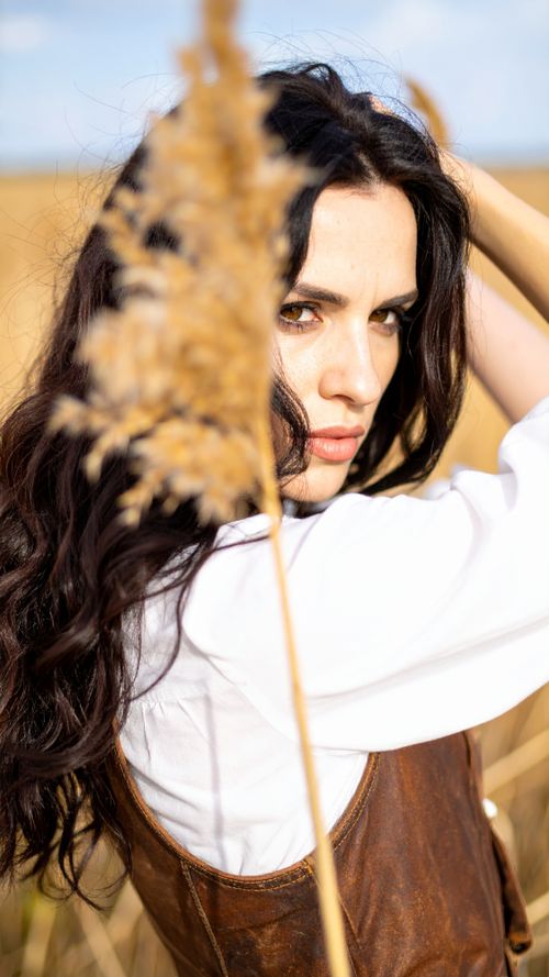 Free Elegant woman in white shirt posing in sunlit Kansas City field. Stock Photo