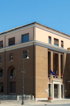 A classic European building with international flags under a clear blue sky.