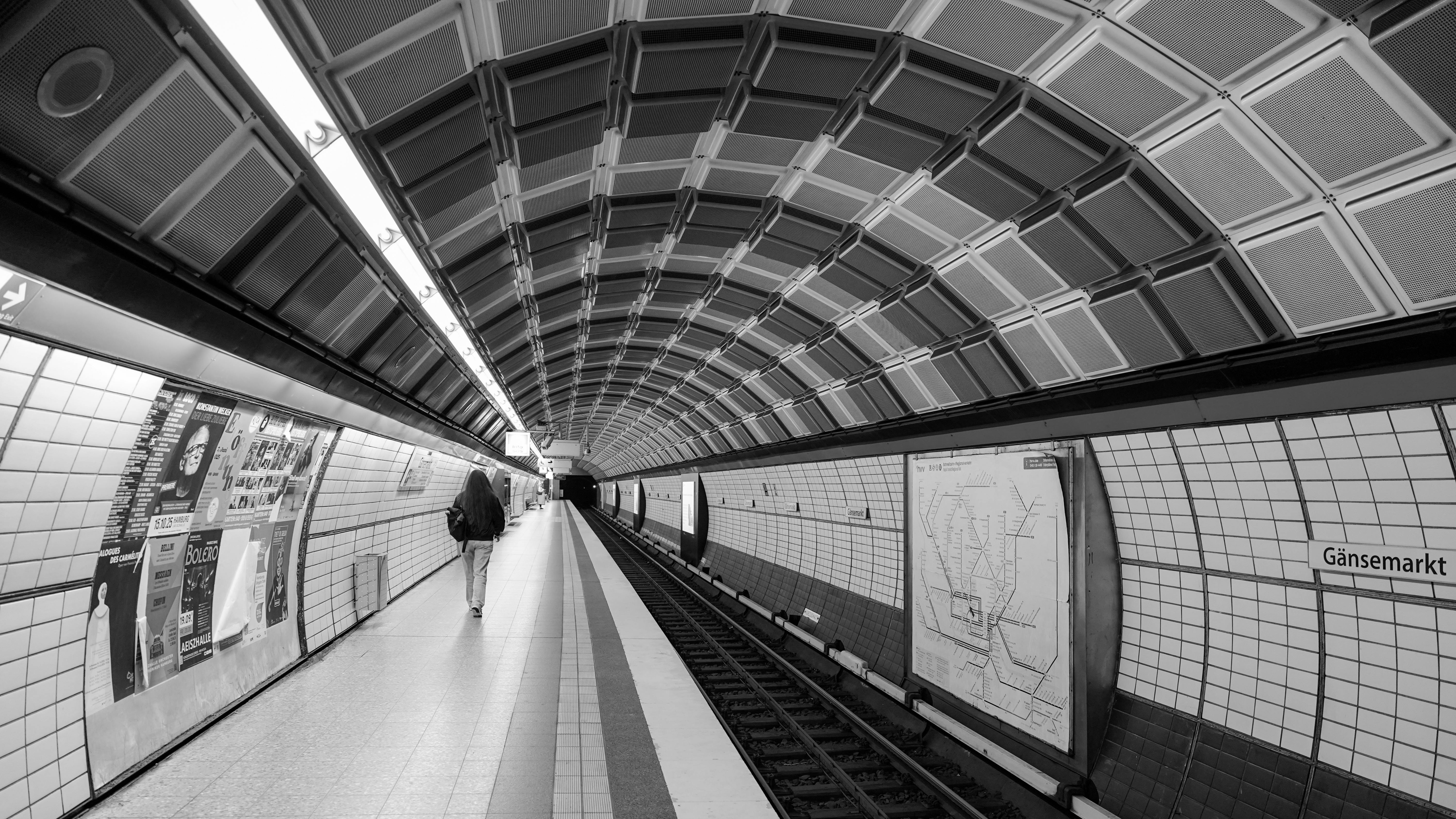Black and white view of Gänsemarkt subway station in Hamburg, showcasing tunnel architecture.