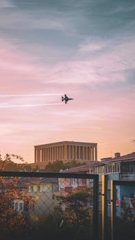 Military jet flying over Anıtkabir in Ankara during a dramatic autumn sunset.