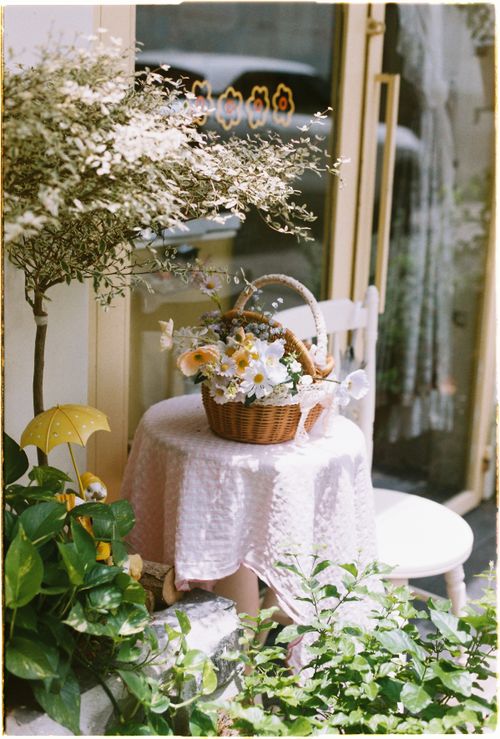 Free A quaint wicker basket with flowers on a small outdoor table. Stock Photo