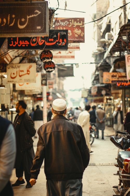 Free A busy market street in Peshawar featuring shoppers, vendors, and traditional architecture. Stock Photo