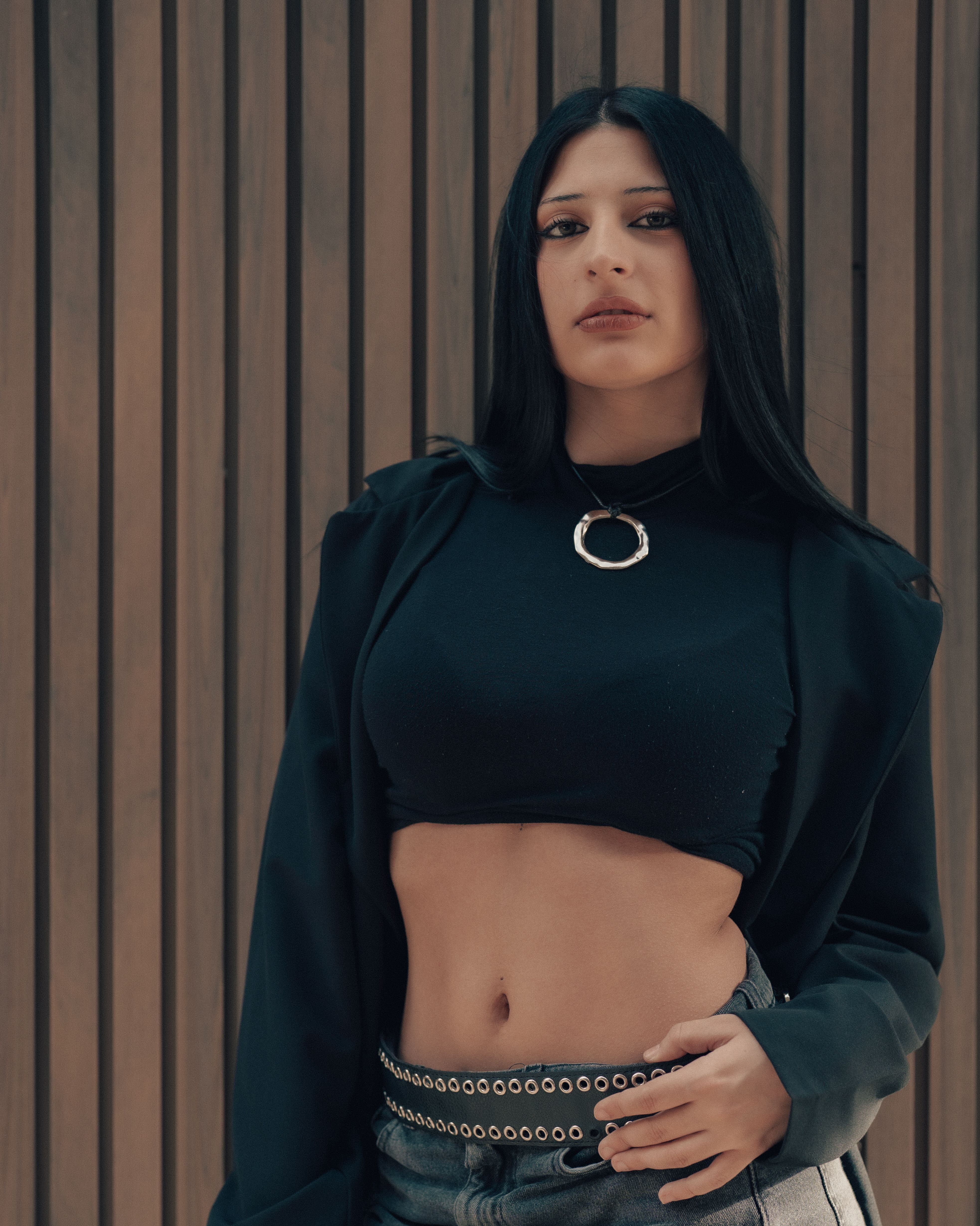 Stylish woman with long hair poses confidently against a wooden panel backdrop, showcasing trendy fashion in Buenos Aires.