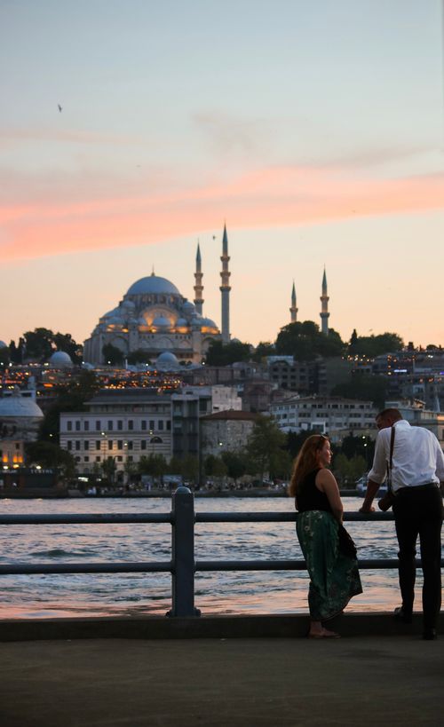 Free A couple enjoys a romantic evening by the Bosphorus with Istanbul's skyline in the background. Stock Photo
