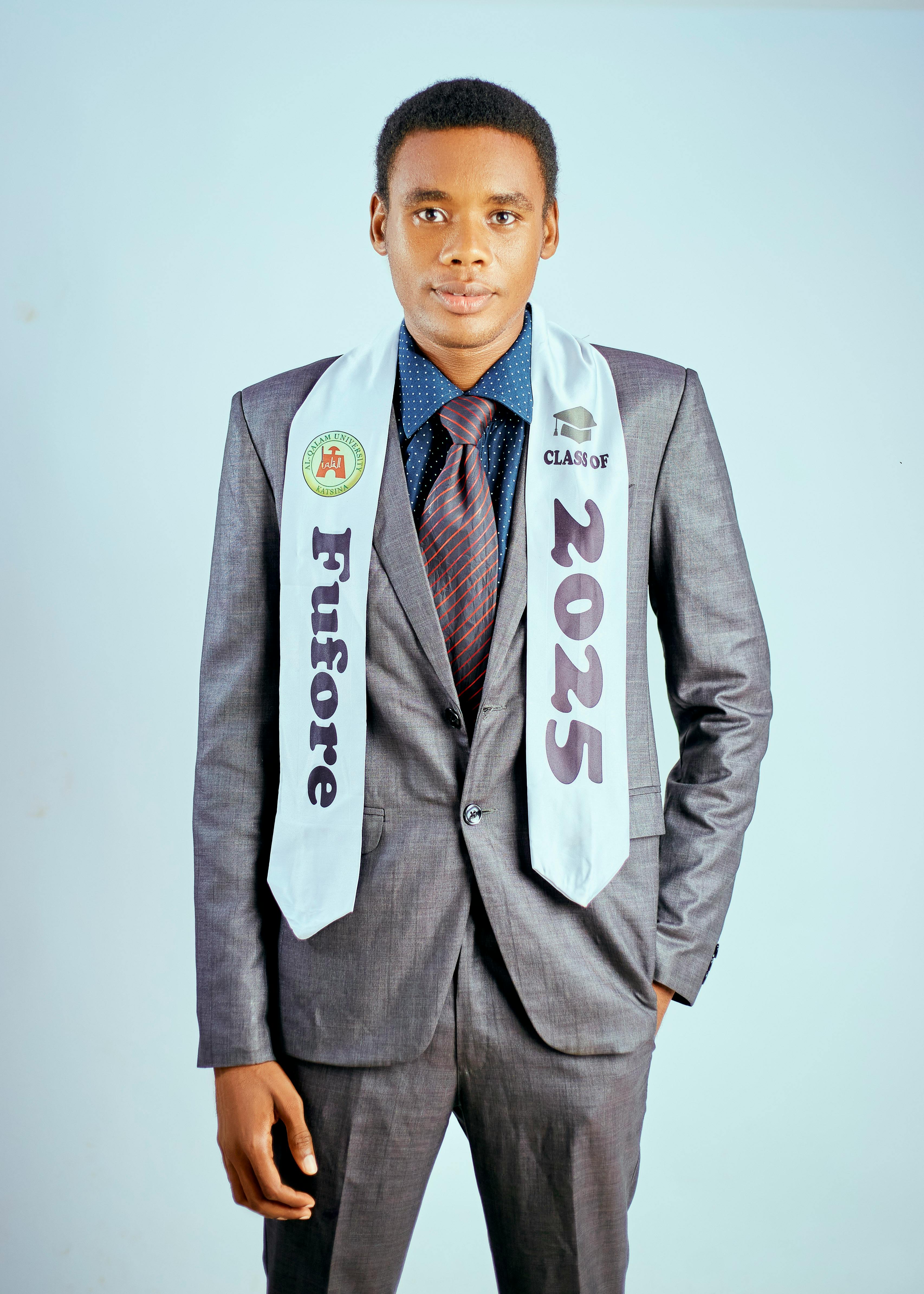 Young adult in formal attire celebrating graduation with a Class of 2025 sash.