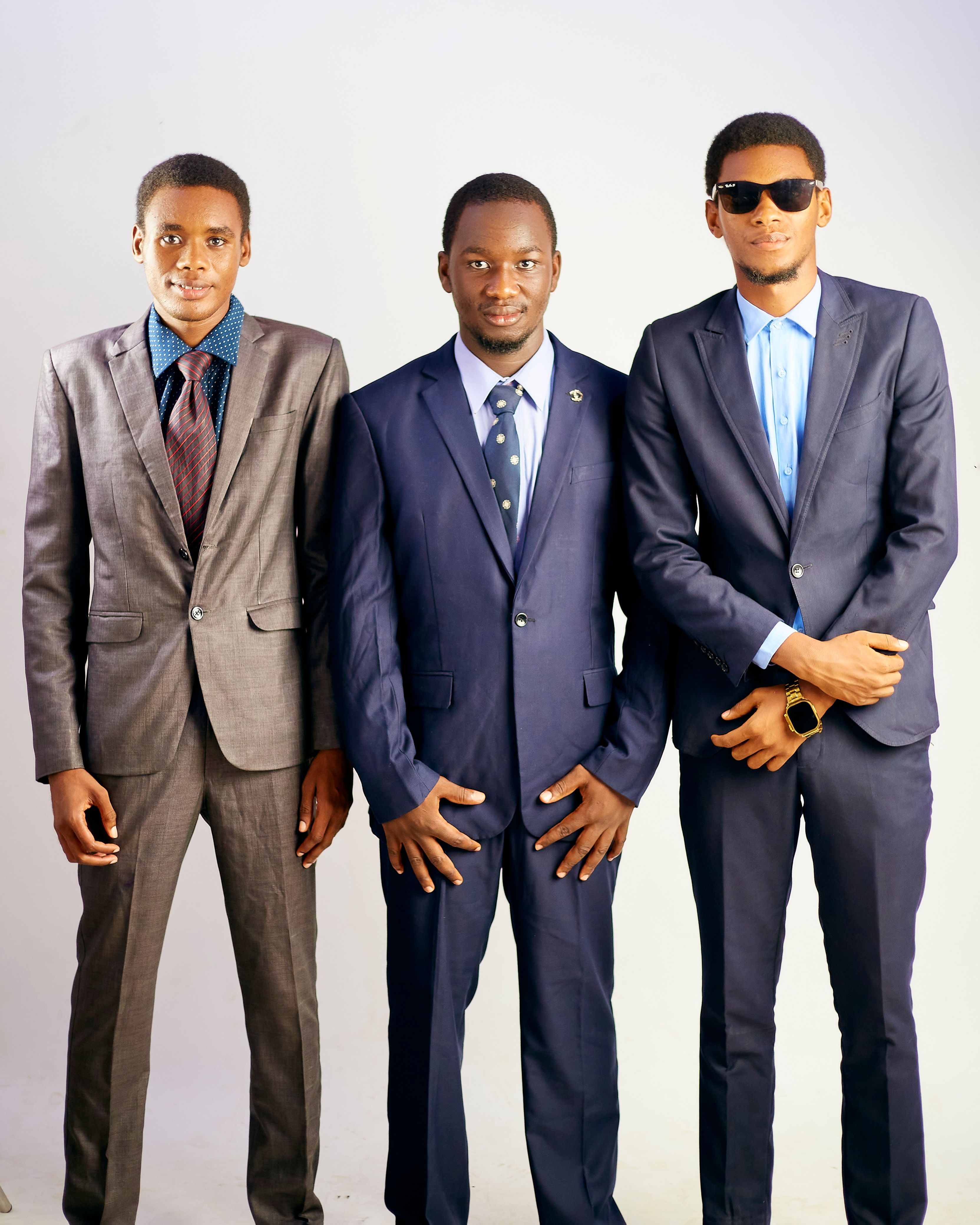 Three confident businessmen posing in suits against a white background.