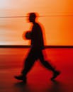 Silhouette of Man Walking Against Vibrant Orange Background