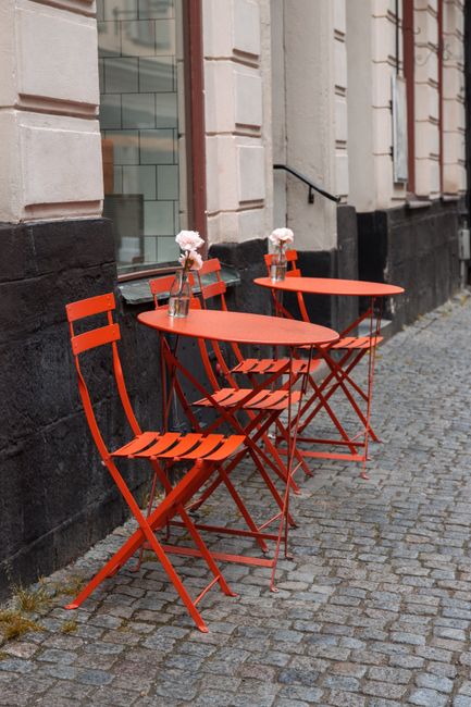 Red outdoor cafe tables and chairs on a cobblestone street in Stockholm, Sweden.