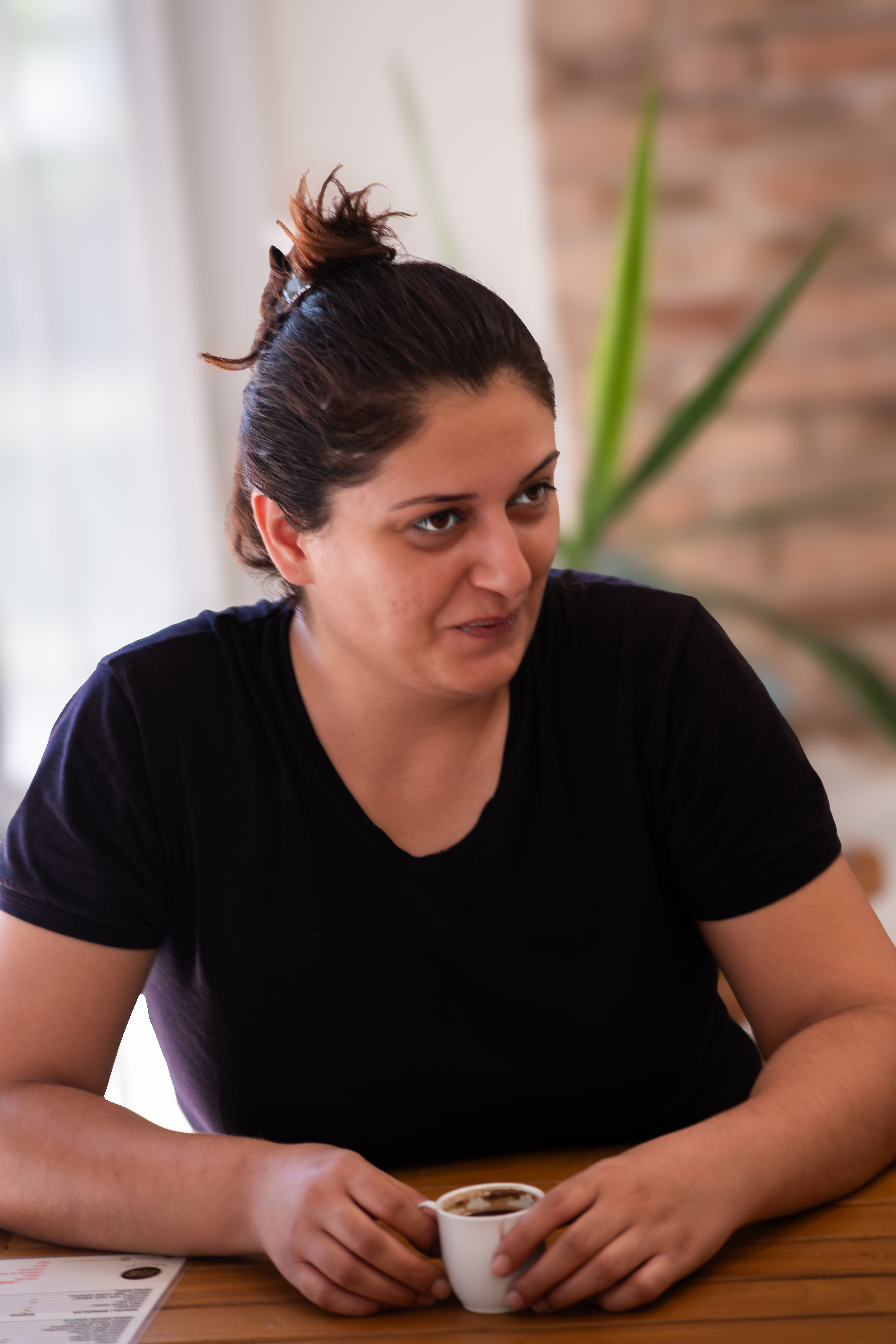 A woman enjoys a moment of relaxation with coffee in a cozy cafe setting, İzmir, Türkiye.