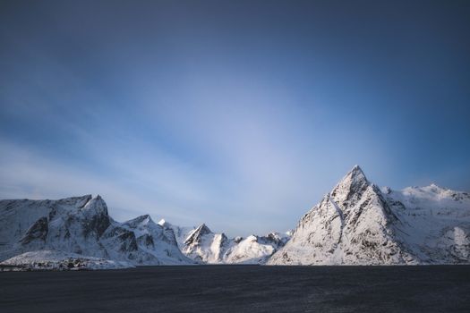 Majestic snow-covered mountains in Lofoten, Norway, under a serene winter sky.