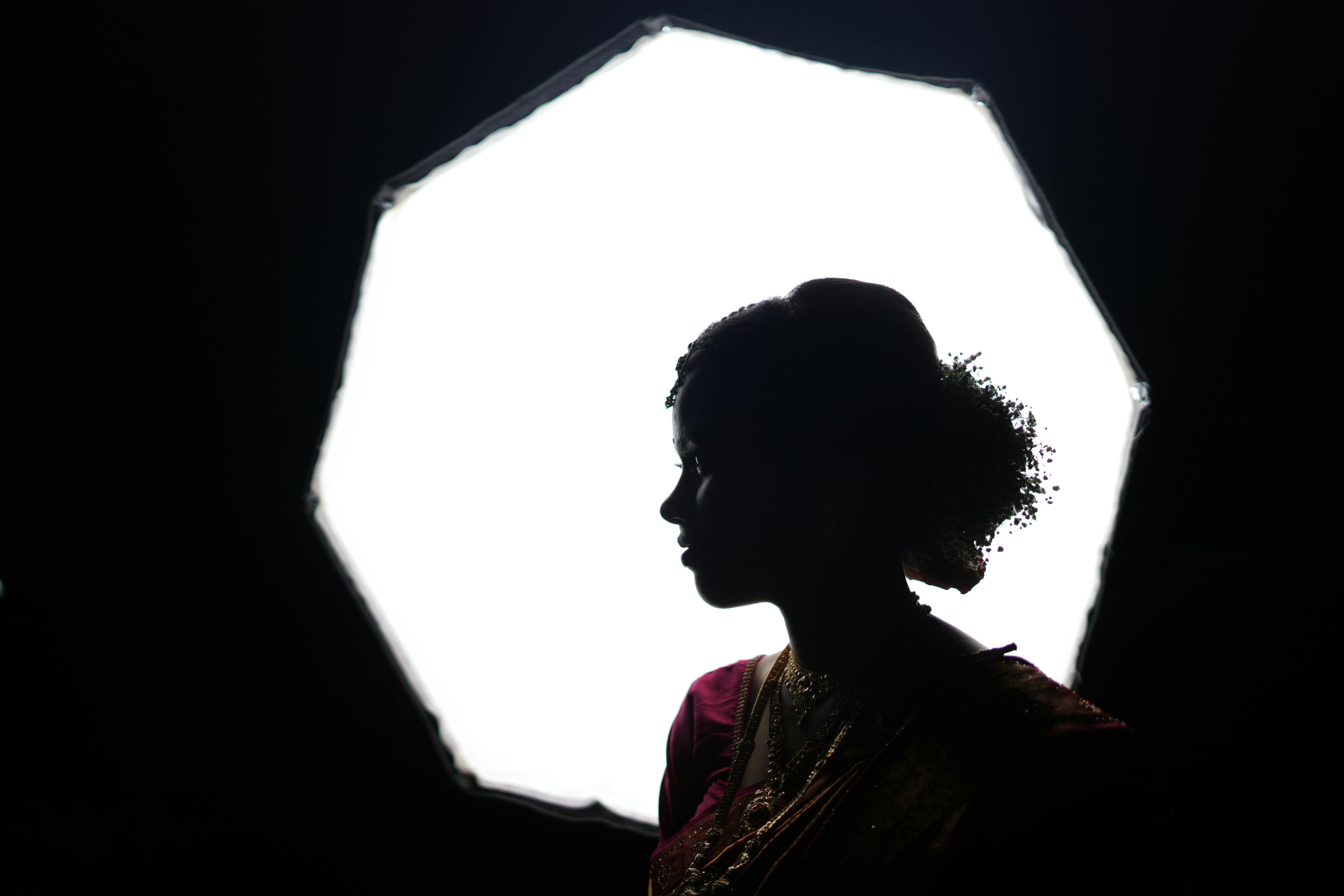 A dramatic silhouette of a woman in traditional attire against a bright softbox.