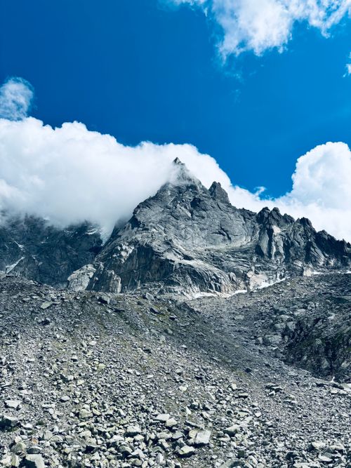 Free Majestic rocky mountain peak under a bright blue sky with scattered clouds. Stock Photo