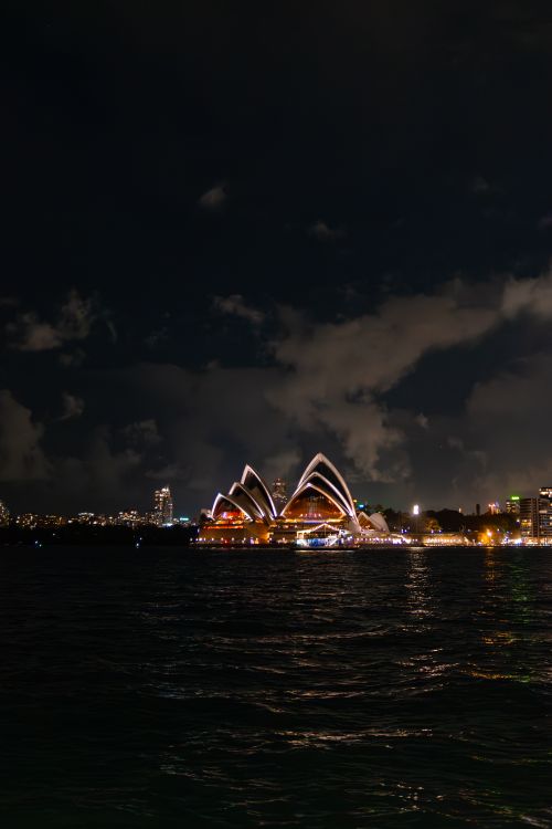 Free Sydney Opera House lights up the night sky with stunning reflections on the water. Stock Photo