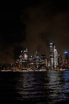 Stunning view of an illuminated city skyline reflected on water during nighttime.