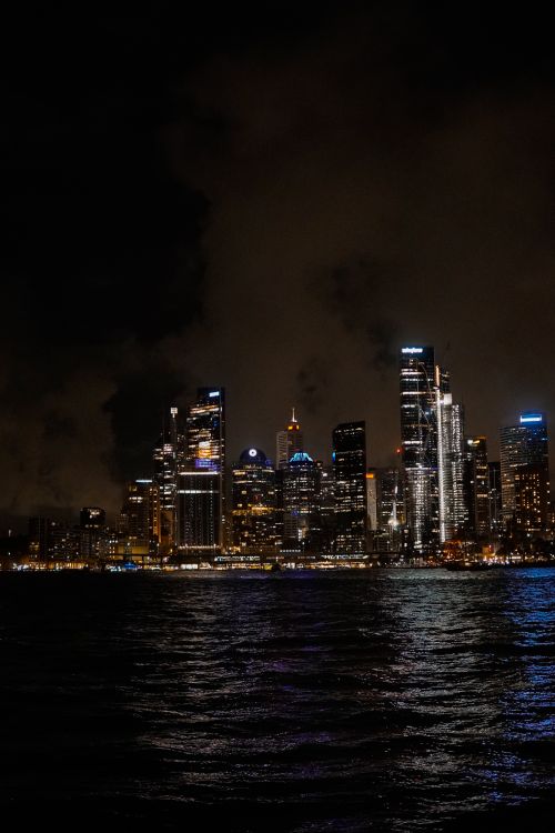 Free Stunning view of an illuminated city skyline reflected on water during nighttime. Stock Photo