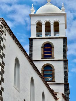 A detailed view of a historic church tower under a clear blue sky in Tenerife, Spain.