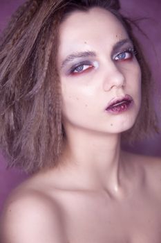 Close-up portrait of a woman with dramatic makeup and textured hair.