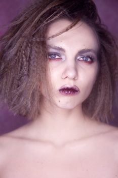 Close-up studio portrait of a woman with striking makeup and hairstyle.