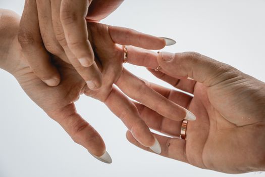 Two adult hands with elegant rings, captured in a soft lighting setup, showing a gesture of tenderness.
