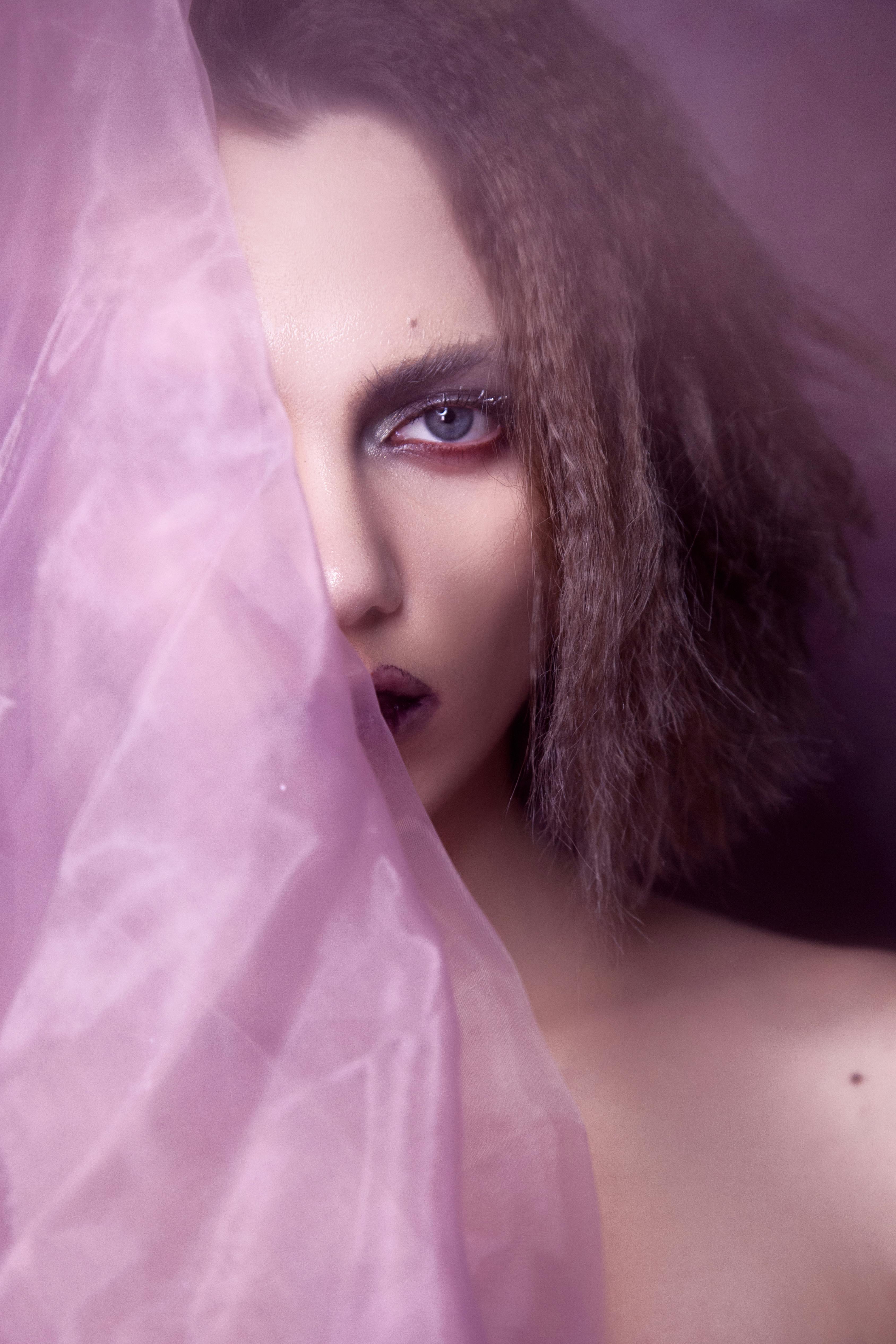 特写艺术肖像中，戏剧性的眼妆与纯粹的紫色面料相得益彰