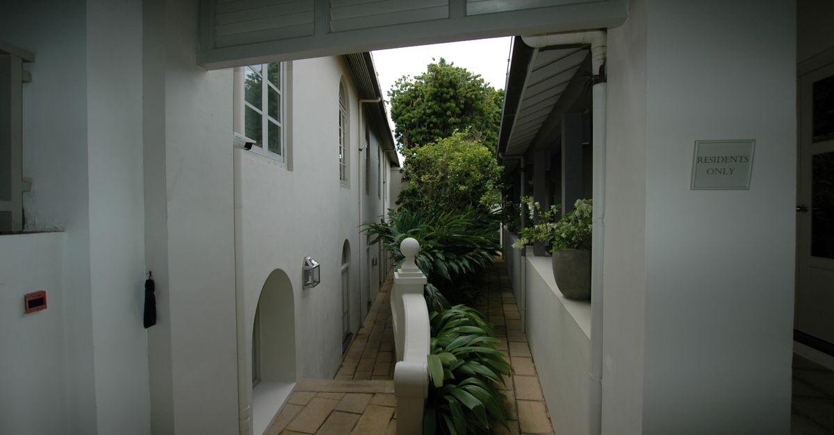A tranquil residential walkway lined with plants and 'Residents Only' sign, exuding a serene atmosphere.