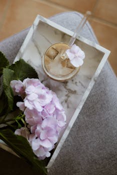 A soft, inviting scene featuring iced coffee and pink hydrangeas on a stylish marble tray.