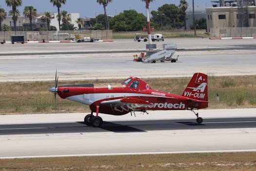A vibrant red Aerotech plane taxiing on the airport runway on a clear day.
