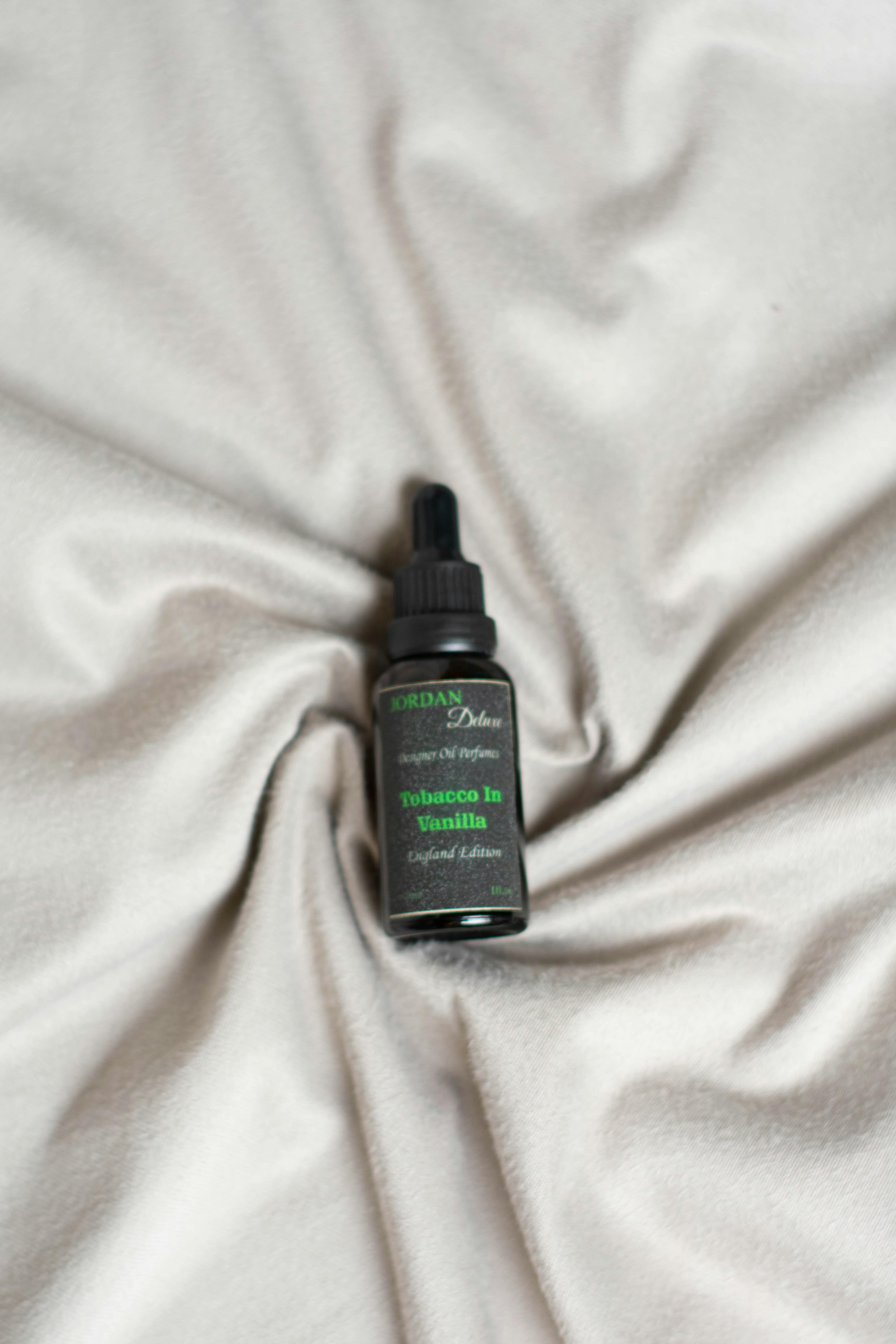 Black essential oil dropper bottle on soft beige fabric, luxurious feel.