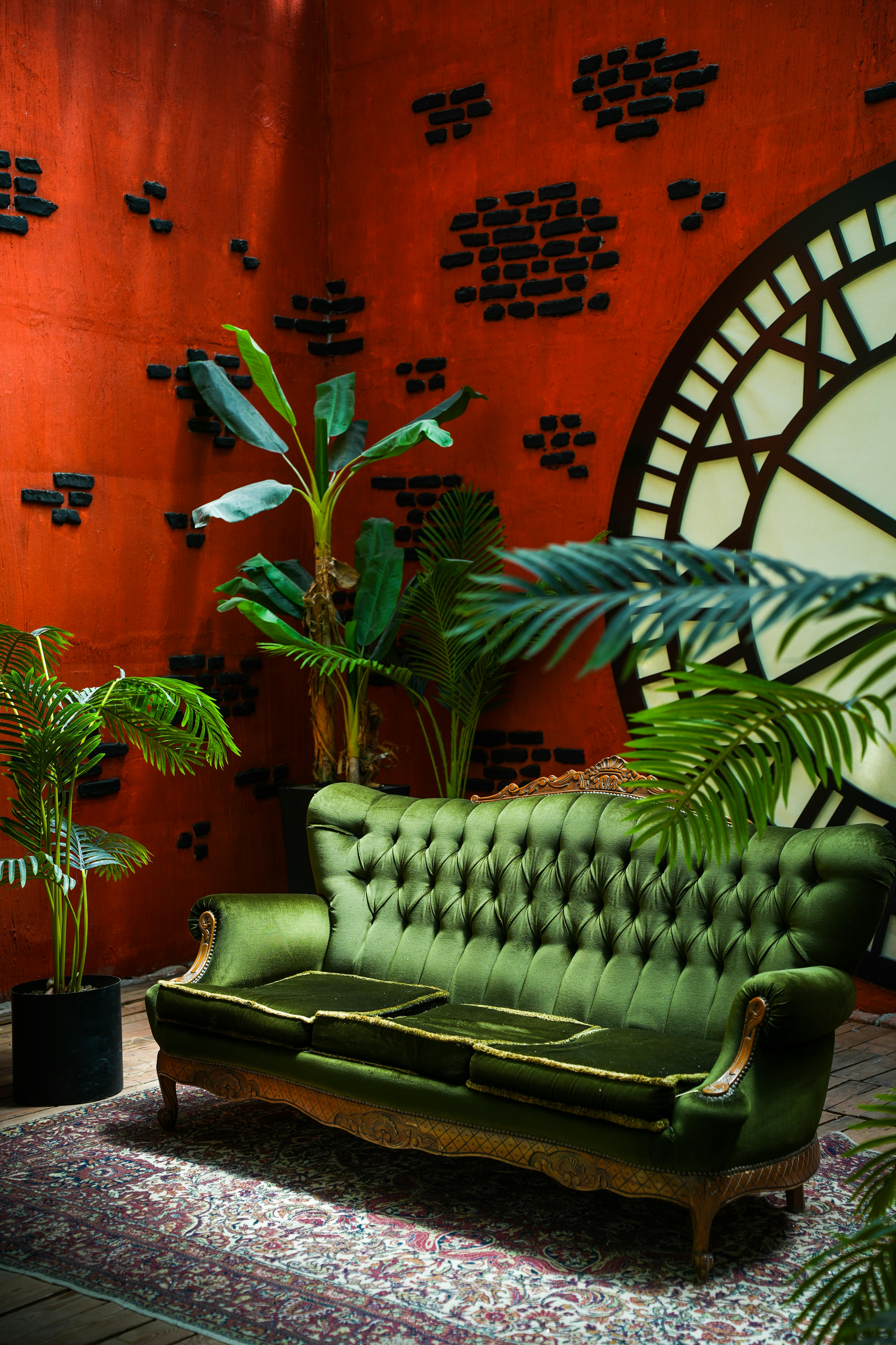 Elegant green sofa in a vintage-style loft with industrial decor and greenery.