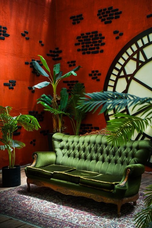 Free Elegant green sofa in a vintage-style loft with industrial decor and greenery. Stock Photo