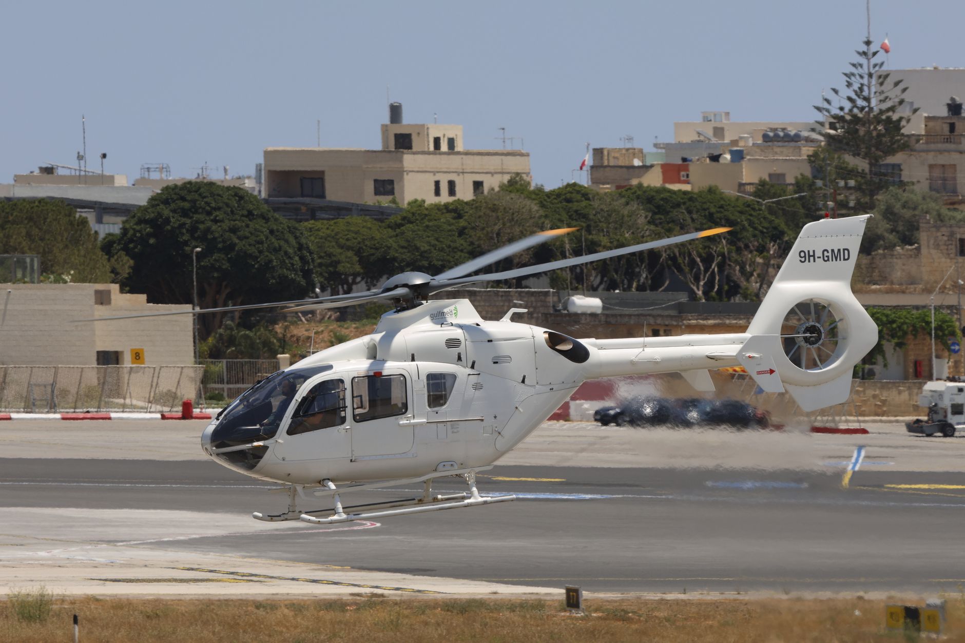 White helicopter landing on a sunny day at an airport in Malta.
