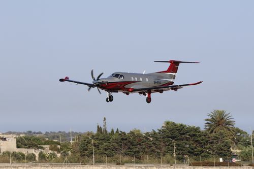 Free Private plane with unique red and gray design approaching landing outdoors on a clear day. Stock Photo