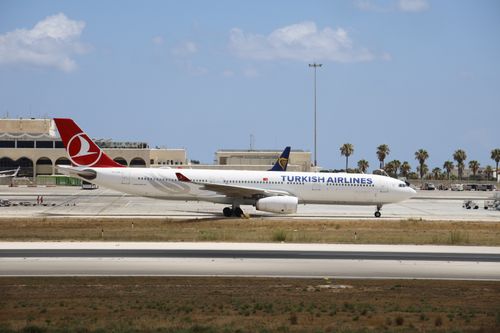 Free Turkish Airlines airplane taxiing on a sunny airport runway with clear skies. Stock Photo