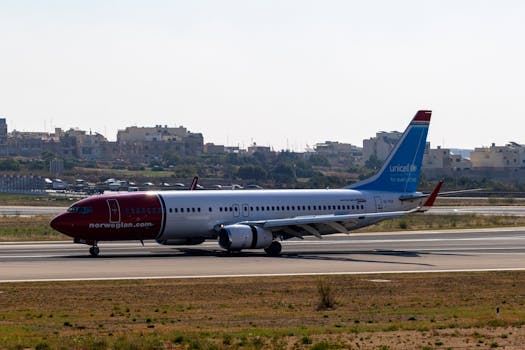 A Norwegian Air plane taxiing at Malta International Airport in daytime.
